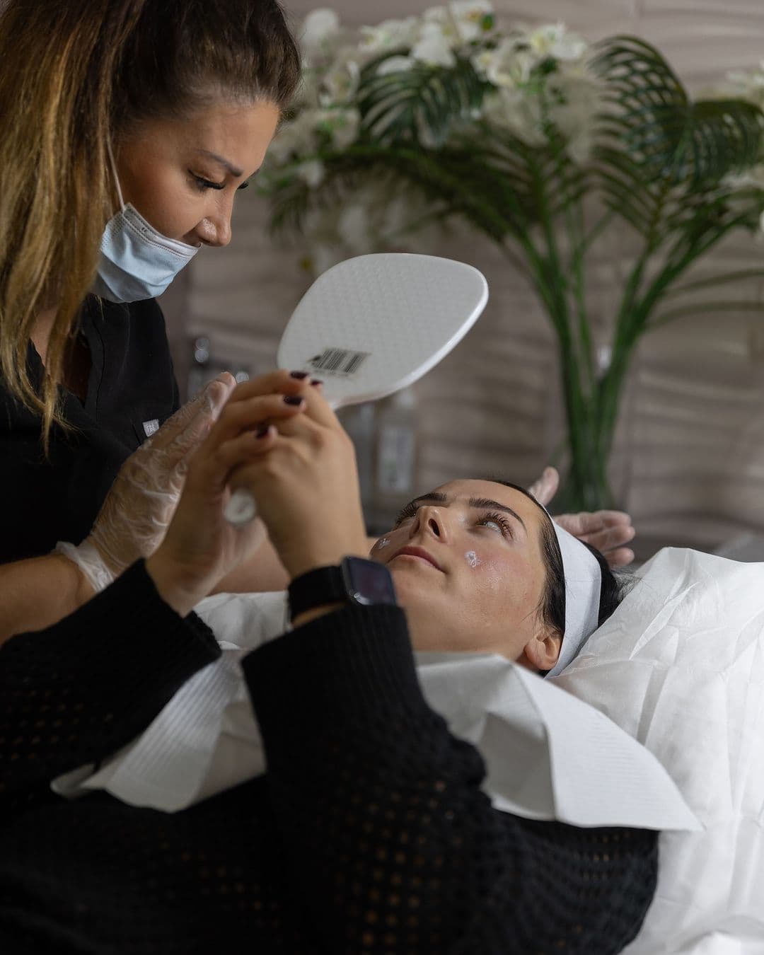 A client reviewing treatment in clinic with a hand mirror